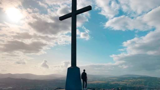 Person standing by huge cross overlooking a landscape