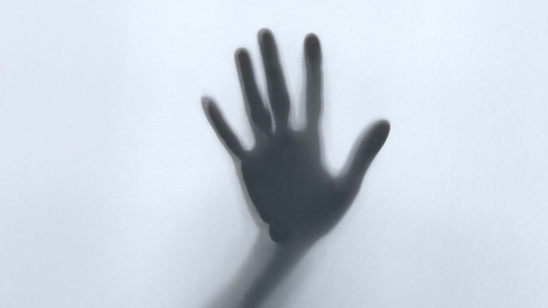 hand on glass asking for help