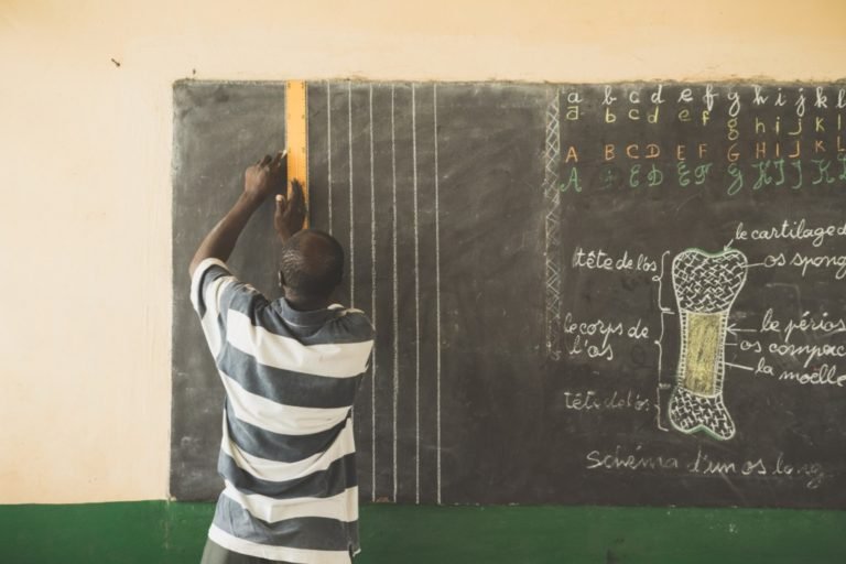 teacher writing on a black chalk board