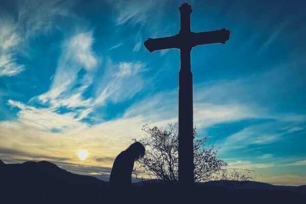 person kneeling before a cross