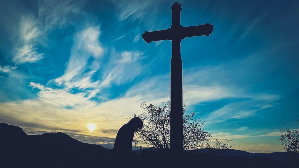 Person bowing before a cross