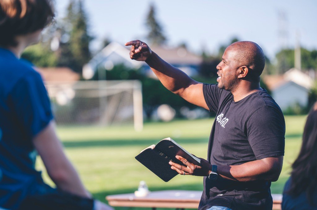 Man preaching the gospel to a group of young people (Photo by Ben White on Unsplash)